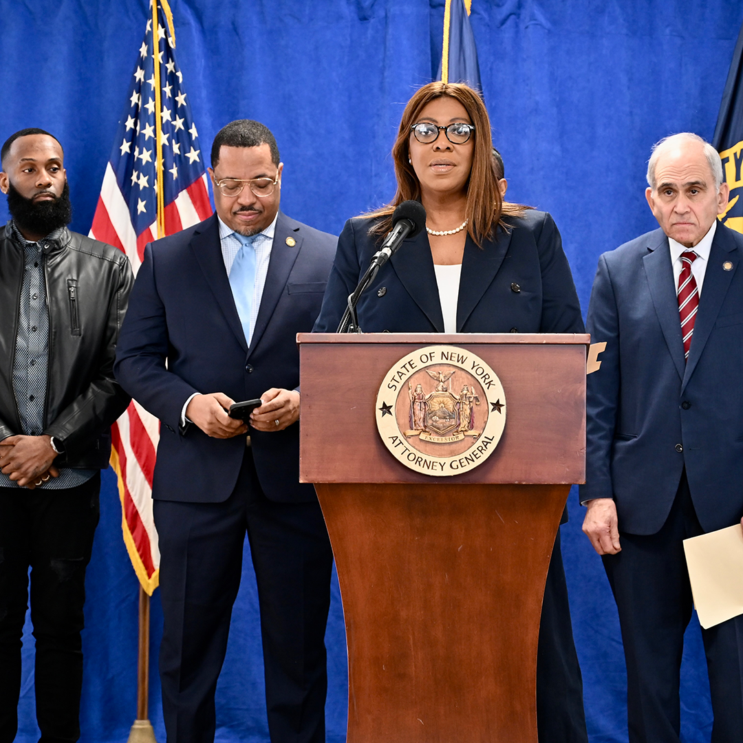 AG James at a podium with people behind her