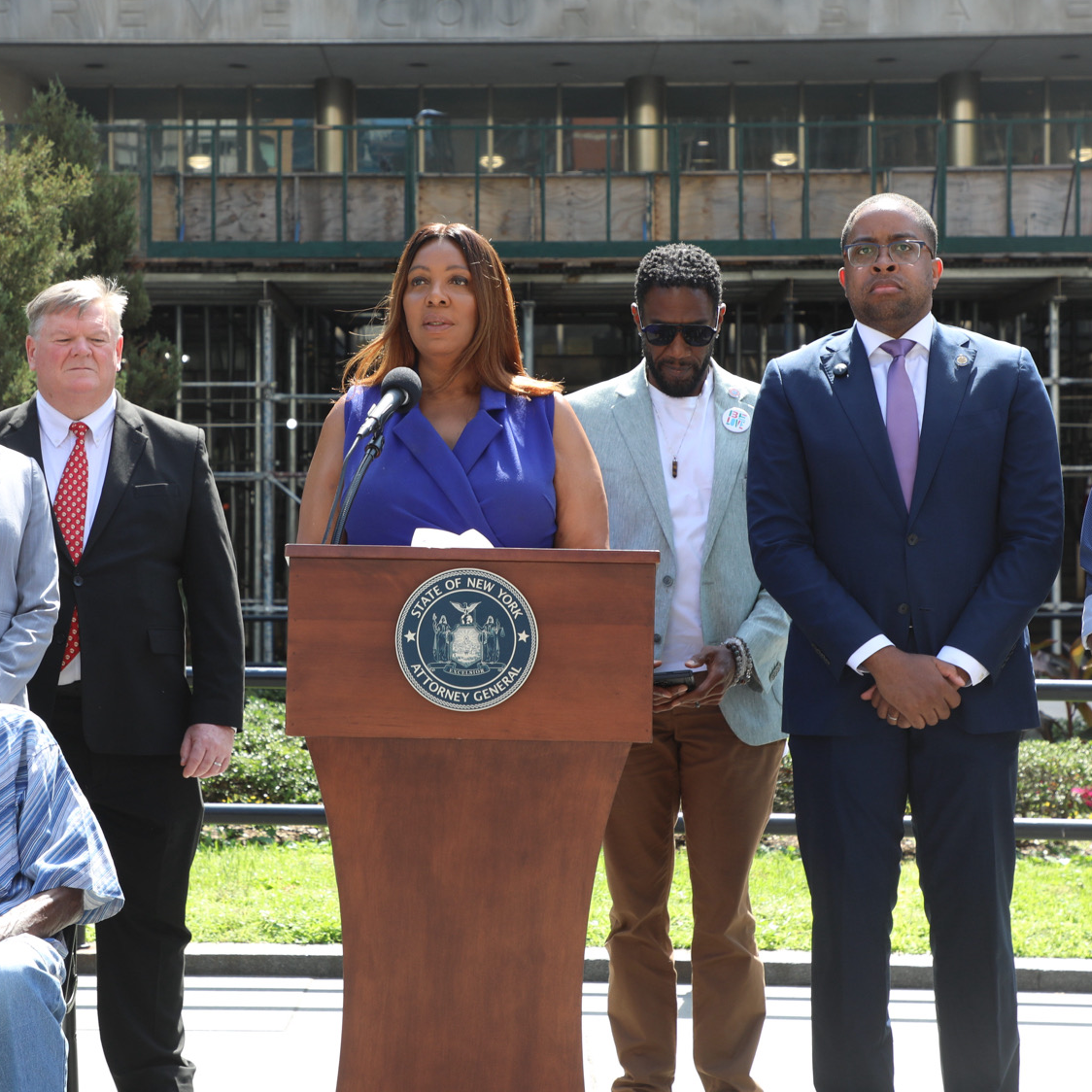 AG James at a podium with people behind her