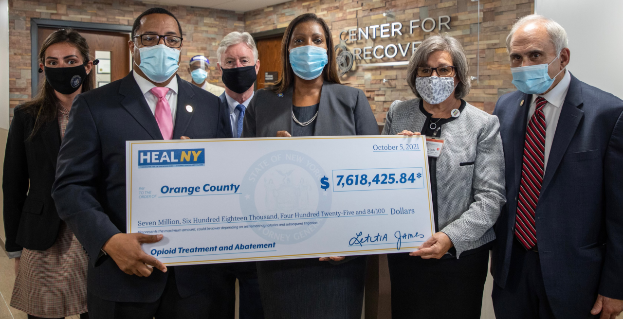 AG James with a group of people holding a check for over $7 million